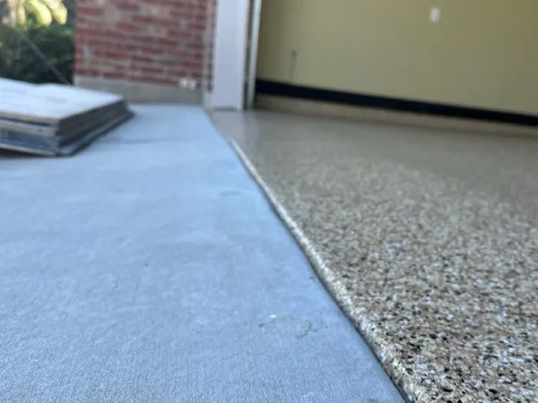 Tan flake coated floor next to bare concrete by Panther Coatings